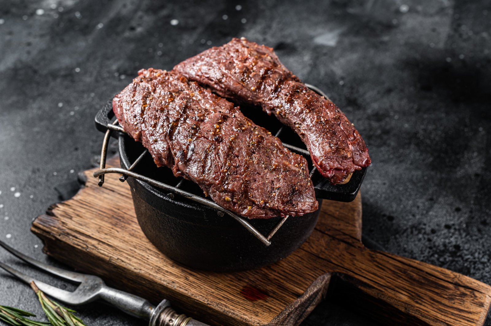 Grilled Machete skirt steak on grill. Black background. Top view